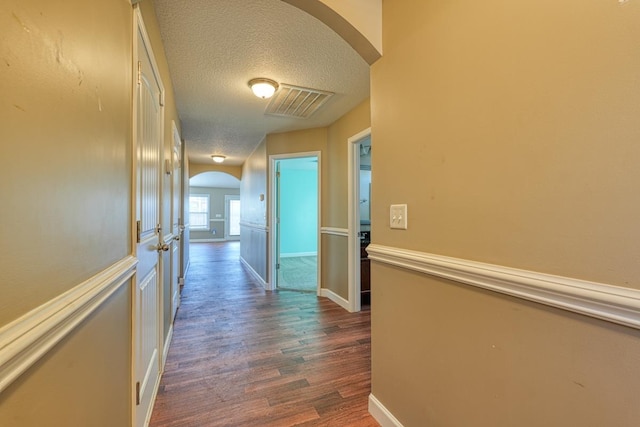 corridor featuring a textured ceiling and dark wood-type flooring