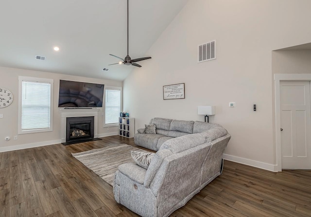 living room with plenty of natural light, ceiling fan, and dark wood-type flooring