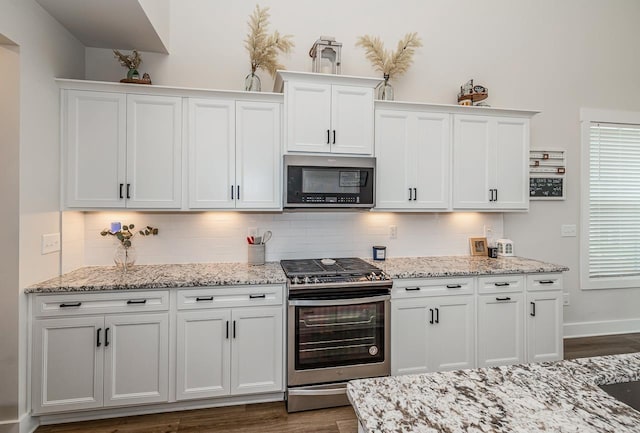 kitchen with tasteful backsplash, white cabinets, stainless steel appliances, and dark hardwood / wood-style floors