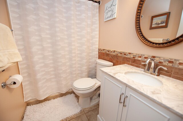 bathroom with tile patterned floors, vanity, toilet, and tile walls