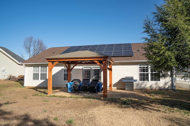 rear view of property with a gazebo, a patio area, a lawn, and solar panels