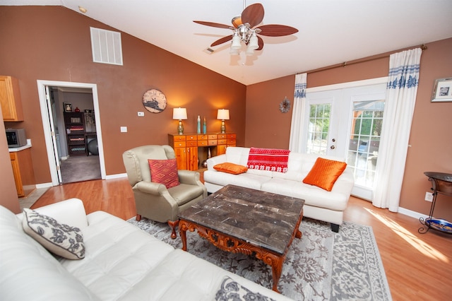 living room with ceiling fan, light hardwood / wood-style floors, vaulted ceiling, and french doors