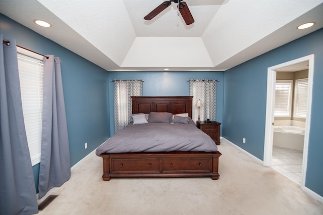 carpeted bedroom with ceiling fan, connected bathroom, and a tray ceiling