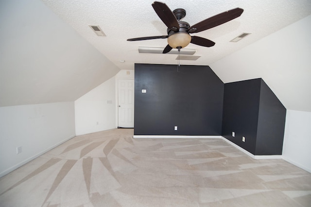 bonus room featuring a textured ceiling, light colored carpet, vaulted ceiling, and ceiling fan