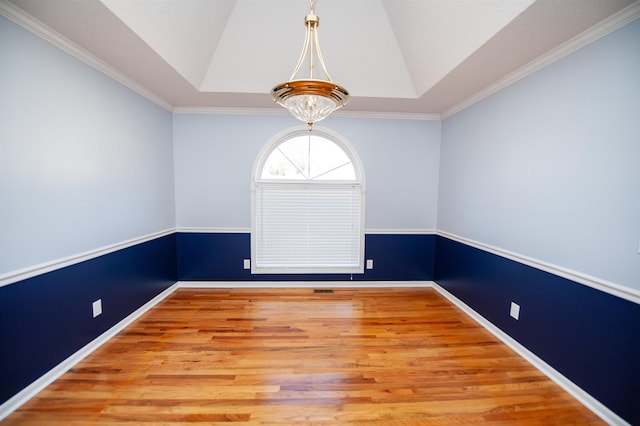 empty room featuring hardwood / wood-style floors, a raised ceiling, and crown molding