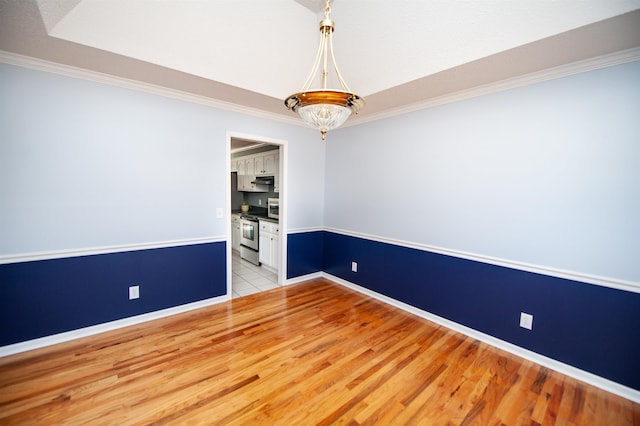 spare room featuring light wood-type flooring and crown molding