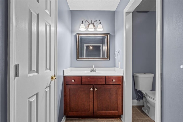 bathroom with tile patterned flooring, vanity, a textured ceiling, and toilet