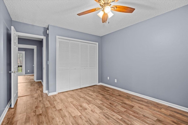 unfurnished bedroom with light wood-type flooring, a textured ceiling, a closet, and ceiling fan