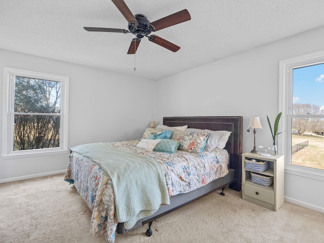 bedroom with ceiling fan, light colored carpet, and a textured ceiling