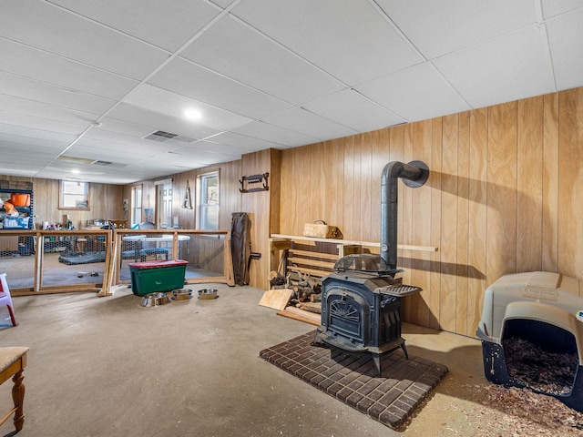 interior space featuring a wood stove, a paneled ceiling, and wooden walls