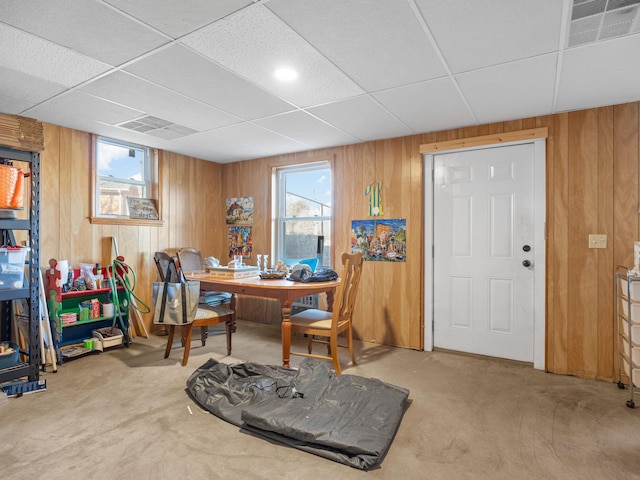 carpeted office space with a paneled ceiling and wooden walls