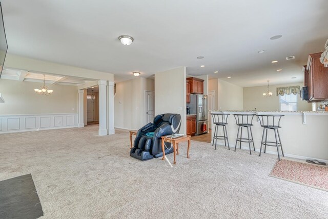 living room featuring beamed ceiling, light colored carpet, decorative columns, and an inviting chandelier