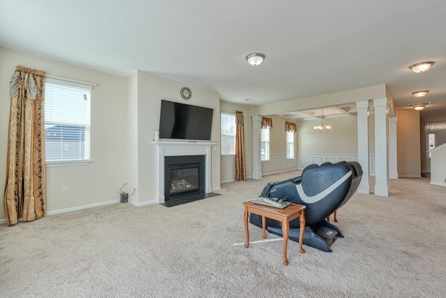 carpeted living room featuring plenty of natural light, ornate columns, and a chandelier