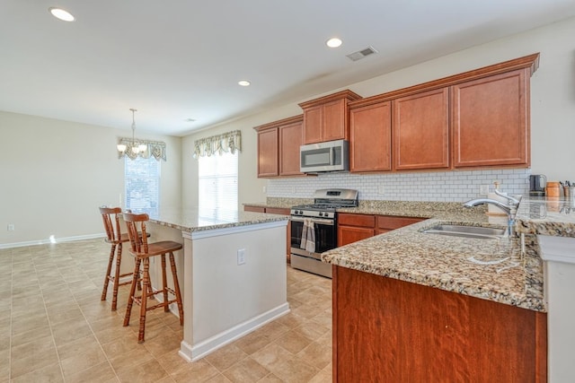 kitchen with pendant lighting, an inviting chandelier, sink, a kitchen island, and stainless steel appliances