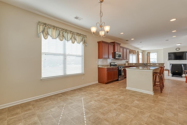 kitchen with a kitchen bar, appliances with stainless steel finishes, backsplash, a chandelier, and hanging light fixtures