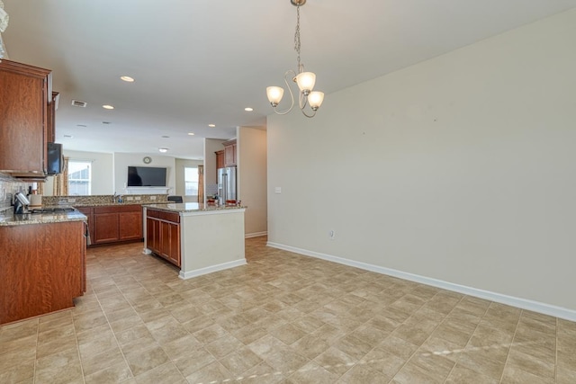 kitchen with sink, stainless steel fridge, pendant lighting, a chandelier, and a kitchen island