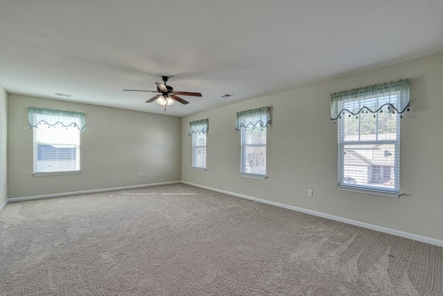 carpeted spare room featuring plenty of natural light and ceiling fan