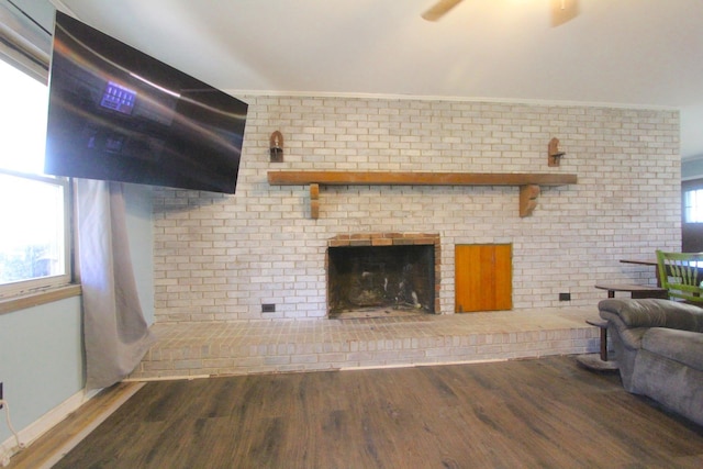 living room with a fireplace, dark hardwood / wood-style flooring, and brick wall