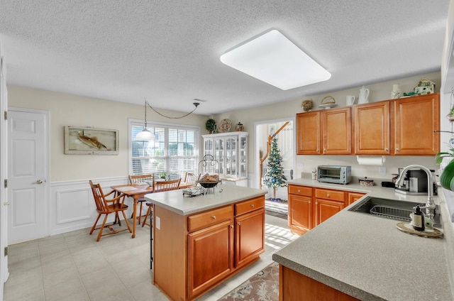 kitchen with a center island, decorative light fixtures, a textured ceiling, and sink