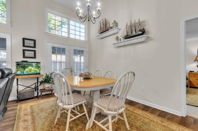 dining area with dark hardwood / wood-style floors, an inviting chandelier, a wealth of natural light, and french doors