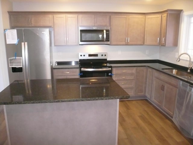 kitchen featuring dark stone countertops, sink, wood-type flooring, and stainless steel appliances