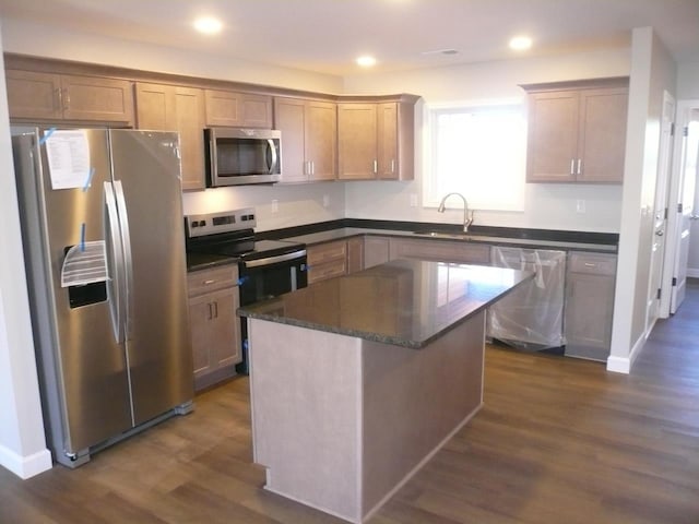 kitchen featuring a center island, dark wood-type flooring, dark stone counters, sink, and stainless steel appliances