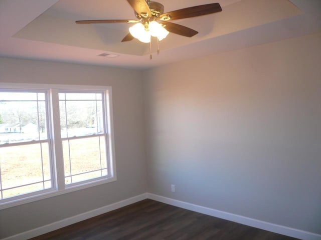 spare room featuring a tray ceiling, ceiling fan, and dark hardwood / wood-style floors