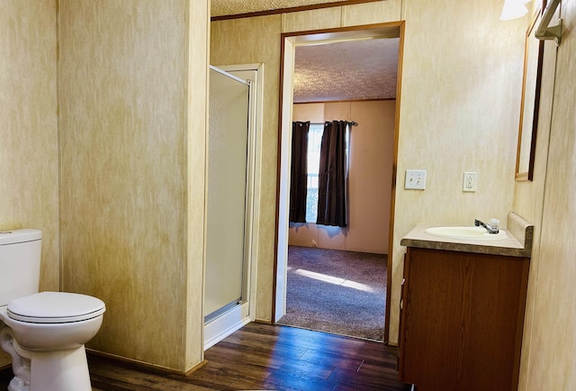 bathroom with an enclosed shower, vanity, a textured ceiling, hardwood / wood-style floors, and toilet