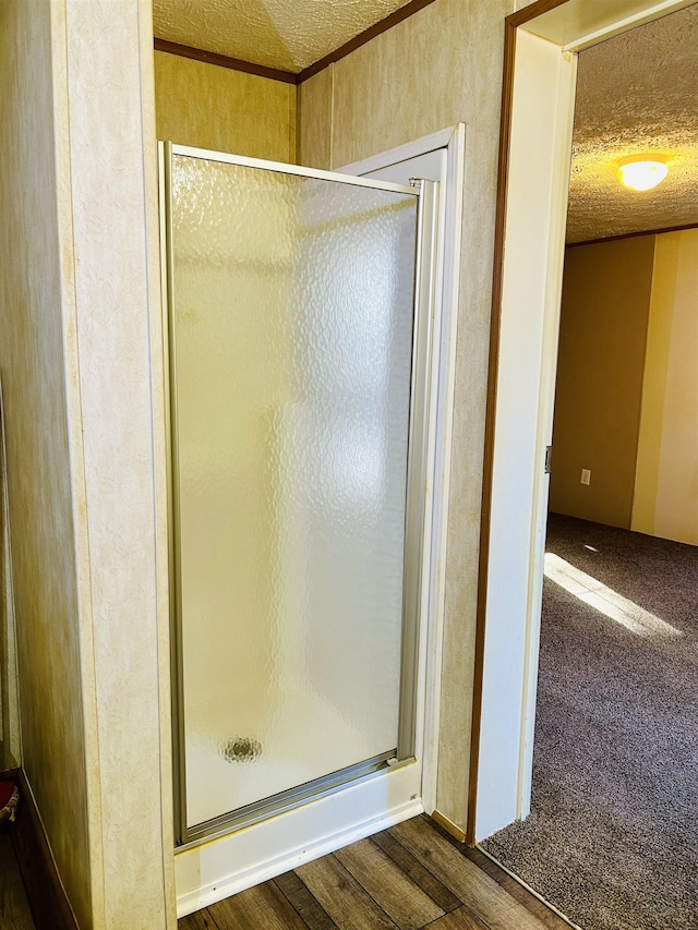 bathroom featuring a shower with shower door, wood-type flooring, and a textured ceiling