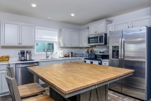 kitchen with a kitchen island, sink, white cabinetry, and stainless steel appliances