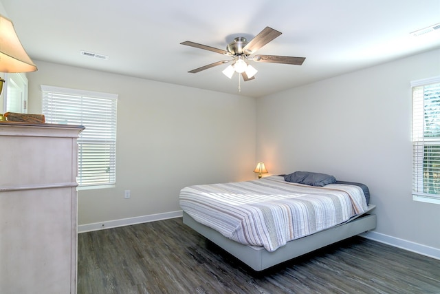 bedroom featuring ceiling fan, dark hardwood / wood-style flooring, and multiple windows