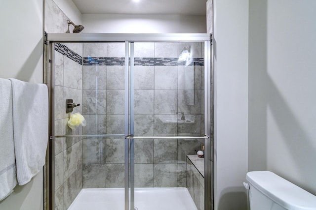 bathroom featuring a shower with door and toilet