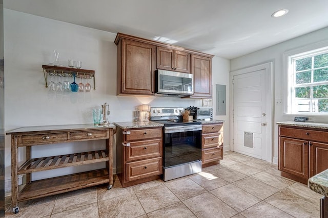 kitchen featuring electric panel, light stone counters, light tile patterned floors, and stainless steel appliances