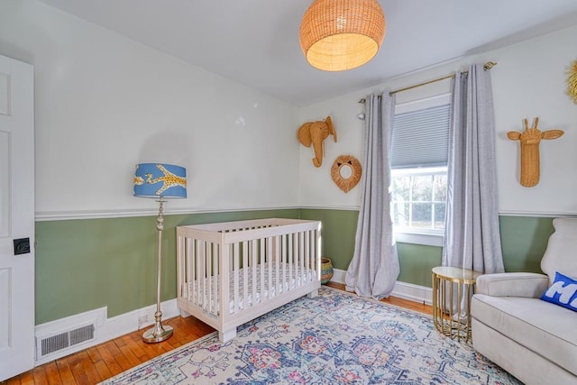 bedroom with hardwood / wood-style floors and a crib