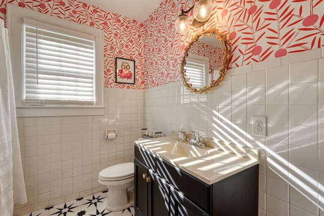 bathroom with vanity, toilet, and tile walls