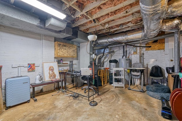 basement featuring electric water heater and brick wall