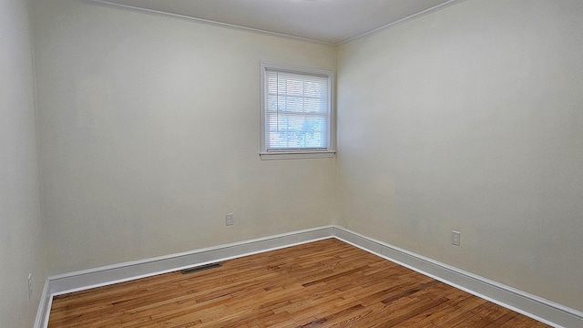 spare room featuring wood-type flooring and ornamental molding