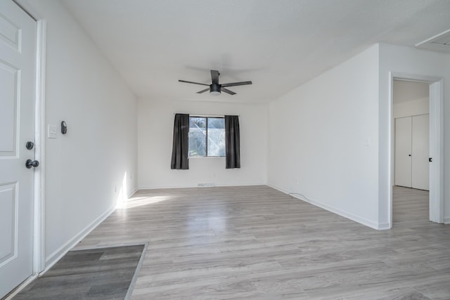 empty room with ceiling fan and light hardwood / wood-style flooring