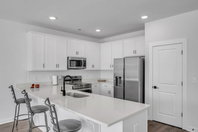 kitchen with kitchen peninsula, stainless steel appliances, white cabinets, and a breakfast bar area