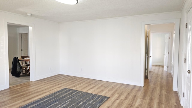 spare room featuring light hardwood / wood-style floors, ornamental molding, and a textured ceiling