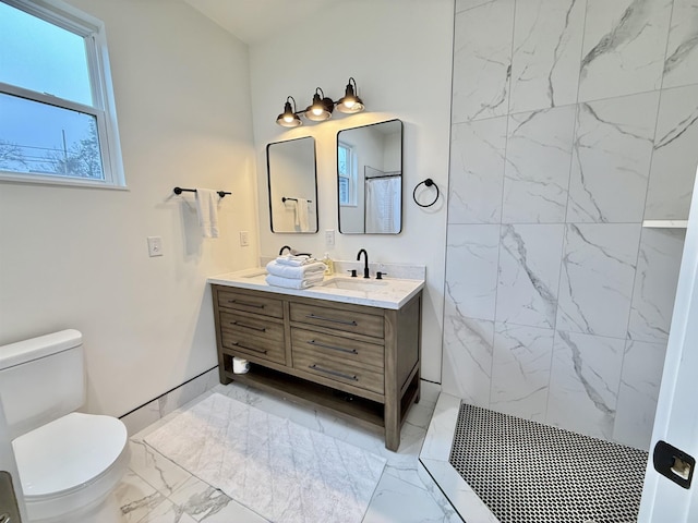 bathroom with vanity, toilet, and tiled shower