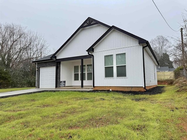 view of front of home with covered porch, a garage, and a front lawn