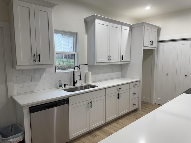 kitchen with backsplash, white cabinetry, sink, and stainless steel dishwasher