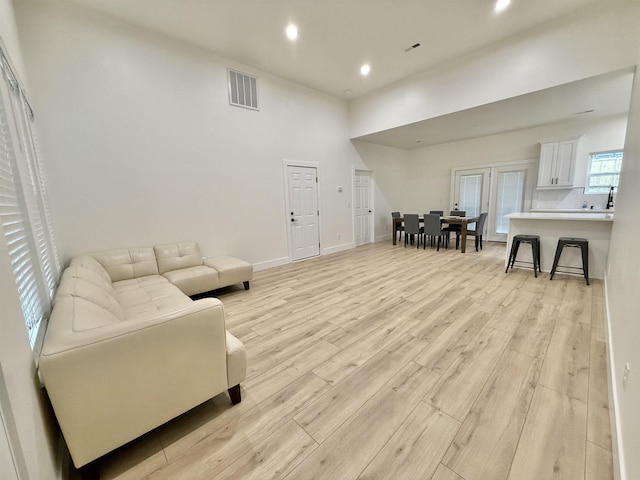 living room with a high ceiling and light hardwood / wood-style floors