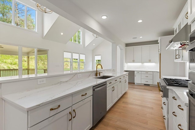 kitchen featuring backsplash, light stone counters, sink, dishwasher, and white cabinetry