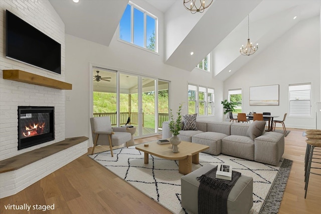 living room featuring a notable chandelier, light wood-type flooring, a towering ceiling, and a fireplace