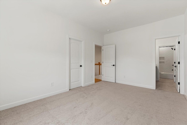 unfurnished bedroom featuring ensuite bathroom and light colored carpet