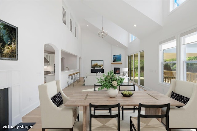 dining room featuring a chandelier, light wood-type flooring, and a towering ceiling