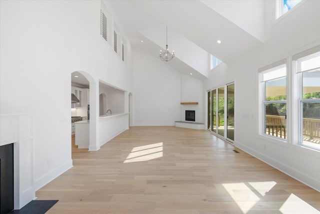 unfurnished living room with a chandelier, a towering ceiling, and a brick fireplace