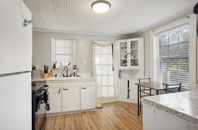 kitchen with ornamental molding, sink, white cabinetry, white fridge, and black electric range oven